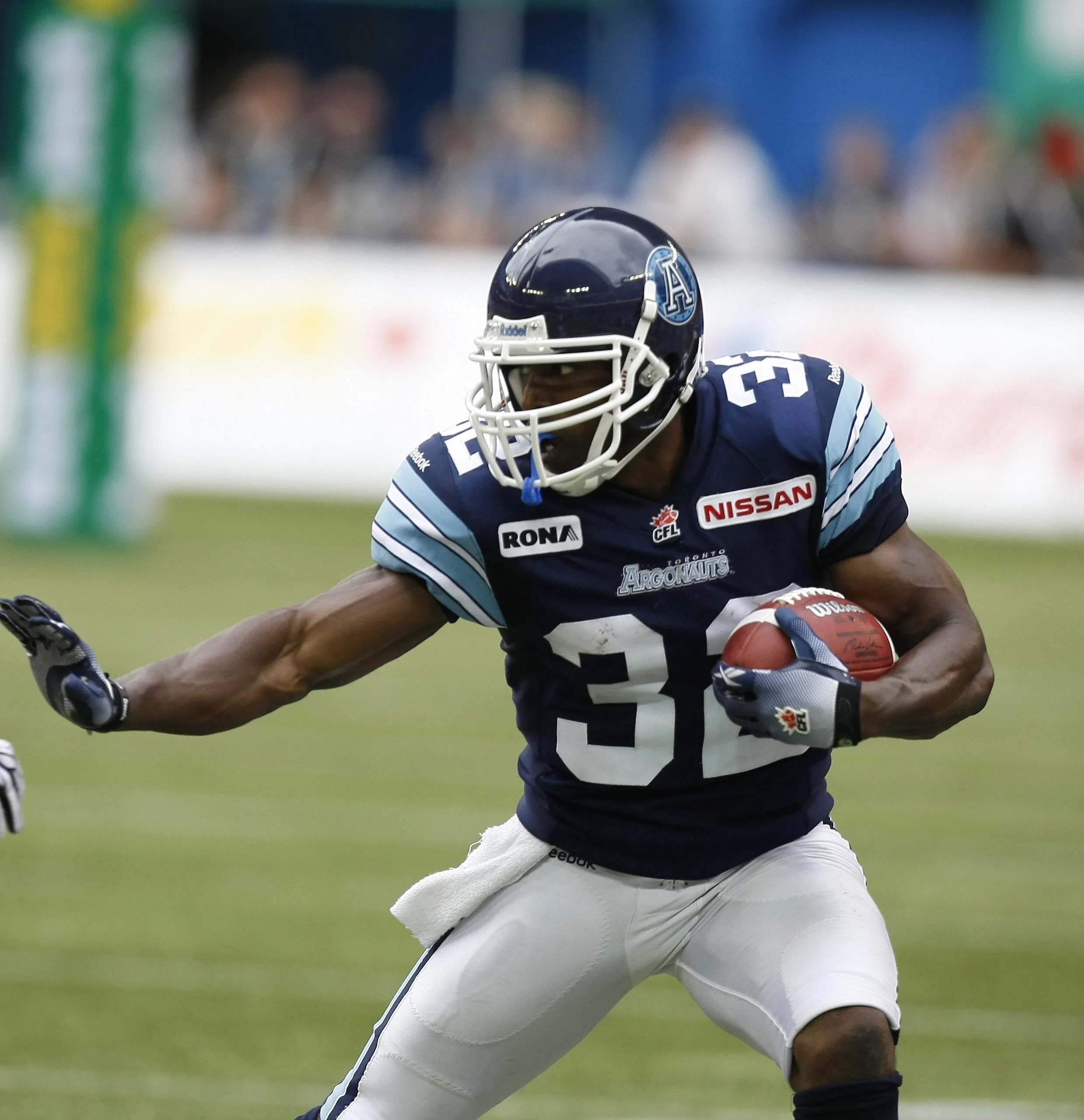 A football player in a navy blue Toronto Argonauts jersey running with the ball