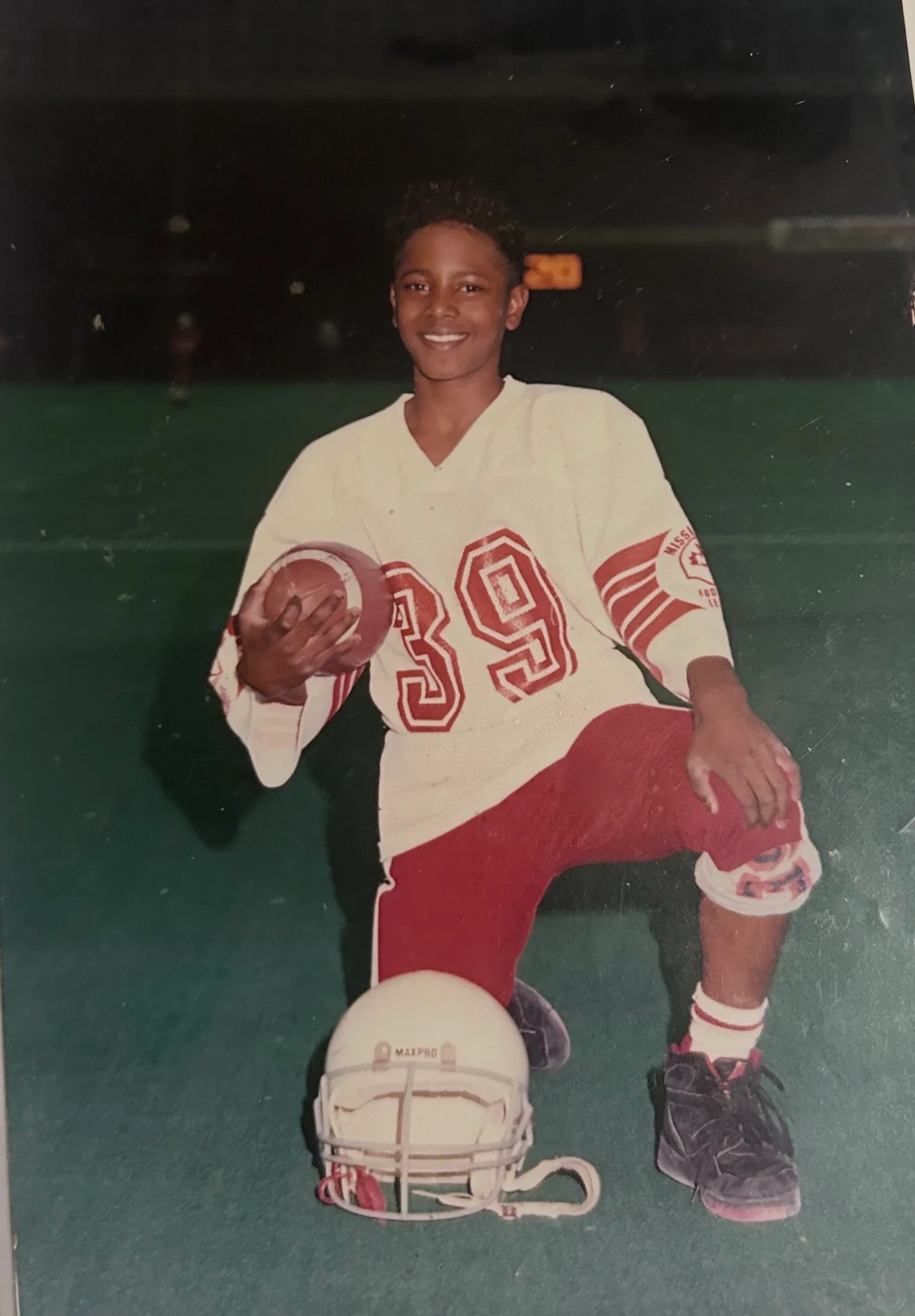 A young football player firing off the line under stadium lights